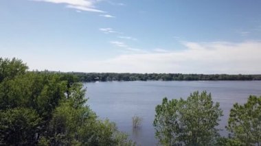 Ağaçların tepesindeki sabit hava aracı görüntüsü yazın Milles-Iles Nehri 'ni nehirden geçerken gösteriyor.