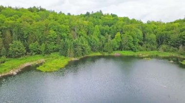 Havanın ortasındaki drone görüntüsü, sakin bir göl üzerinde yavaşça sağa sola dönüyor. Güzel bir yaz gününde, sudaki güzel gökyüzünün yansımasını gösteriyor.