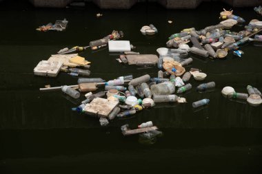 Bangkok, Tayland-22 Nisan 2023: Kirli kanalizasyonlarda yüzen bir sürü plastik şişe ve köpük konteynırı.