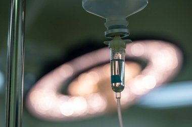 Salin poşetindeki damar içi sıvı ve ameliyathane lambası arka planı..