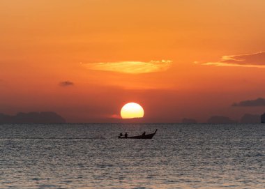 Phuket şehrinde turuncu gökyüzü olan uzun kuyruklu teknenin güzel gündoğumu ve silueti.
