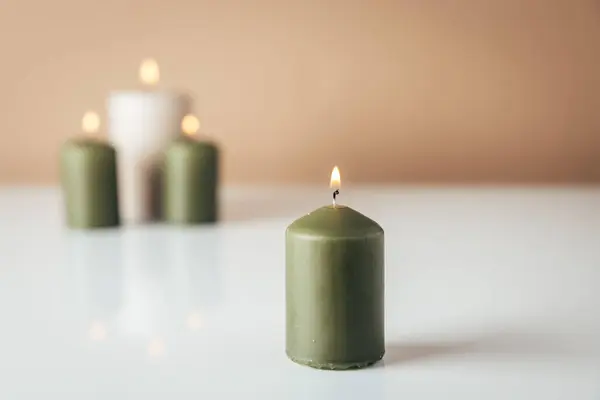 Burning candles in green and beige colors with copysapce