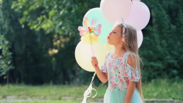 Dziewczynka Balonami Rękach Wieje Wielobarwny Wiatrak Zabawki Naturze Tle Drzew — Wideo stockowe