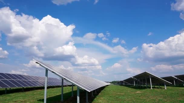緑の芝生と地面に太陽電池パネルの要素と行のインストール 雲と空の背景にフィールドに太陽光発電所 発電所のインフラ — ストック動画