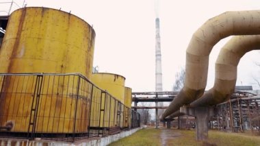 Kimya fabrikasının bölgesindeki büyük sarı sülfürik asit varilleri. Metal ve beton yapılarda paslı borular var..