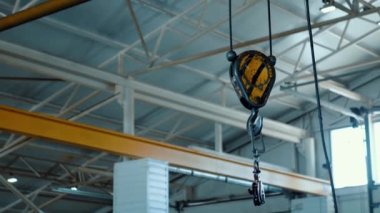 Bir vincin metal endüstriyel kancası yük kaldırmak için kablolarda sendeliyor. Metal yapıları olan depo..