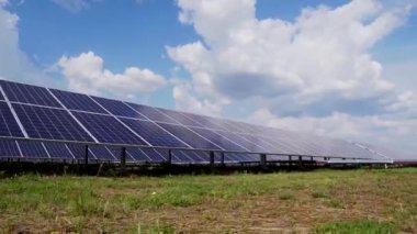 Elektrik üretimi için fotovoltaik güneş panelleri. Yeşil bir alanda güneş enerjisi santrali. Bulutlu gökyüzü.