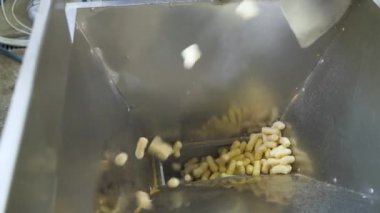 Yiyecek fabrikasındaki metal bir konteynıra abur cubur dökmek. Ürünler için otomatik paketleme hattı.
