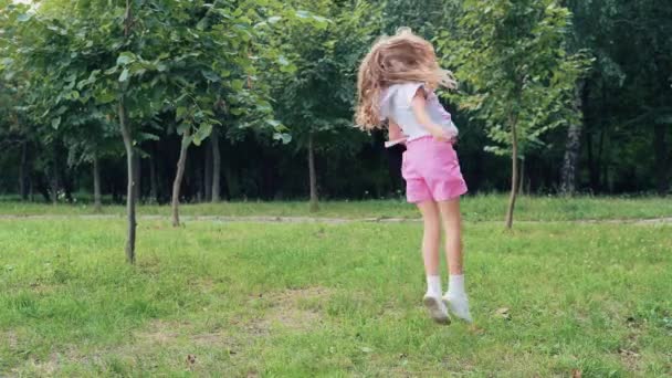 Щаслива Дівчинка Стрибає Танцює Траві Літньому Парку Перехід Коліщатка — стокове відео