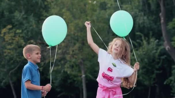 Meisje Een Jongen Het Park Houden Helium Ballonnen Hun Handen — Stockvideo