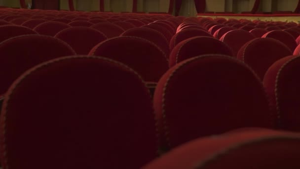 柔らかい赤い生地で装飾されたアンティークのアームチェア 空のオペラハウスで椅子の列 明るいソフトライト — ストック動画