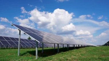 Yerdeki desteklere fotovoltaik güneş panelleri kurulumu. Bulutlu mavi gökyüzüne karşı bir tarlada güneş enerjisi santrali.