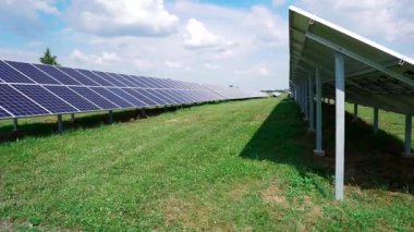 Yeşil çimen tarlasında metal direklere monte edilmiş fotovoltaik silikon paneller. Elektrik üretimi için güneş enerjisi santrali. Yenilenebilir yeşil enerji.