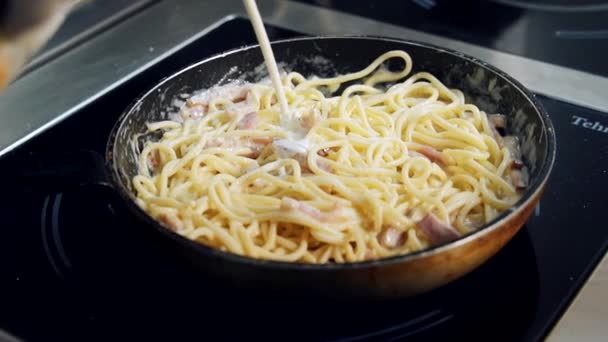 おいしいパスタを調理するプロセス シェフはフライパンでスパゲティ料理に白いソースをかけています クリーミーなパスタを作る — ストック動画