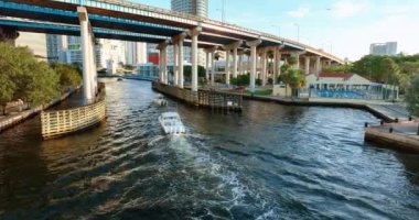 Miami, Florida 'da karayolu köprüsünün altındaki nehirde yüzen tekne. Akşam manzarası. Hava görüntüsü. Miami nehri üzerinde köprüleri olan insansız hava aracı uçuşu.
