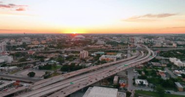 Otoyollarda arabaları, çok katlı kavşakları ve köprüleri olan Miami 'nin akşam manzarası. Ufuktaki sarı güneş.