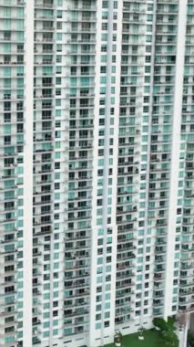 Balkonları ve pencereleri olan çok katlı bir bina. Miami Brickell şehir merkezindeki gökdelen binaları. Amerikan megapolis 'i. Dikey video.