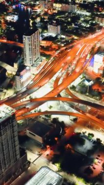 Miami City, Florida 'da gece hızlı giden araba ve kamyonlarla kavşağın hava görüntüsü. Ulaşım altyapısı. Dikey video.