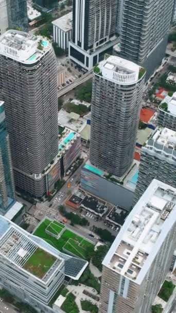 从空中俯瞰市中心的摩天大楼和玻璃建筑 街上有车 有绿色草坪和游泳池的高楼的屋顶 垂直录像 — 图库视频影像