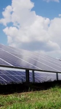 Bir sıra fotovoltaik güneş paneli boyunca yürü. Sahada güneş enerjisi santrali var. Bulutlu gökyüzünün alt manzarası. Dikey video.