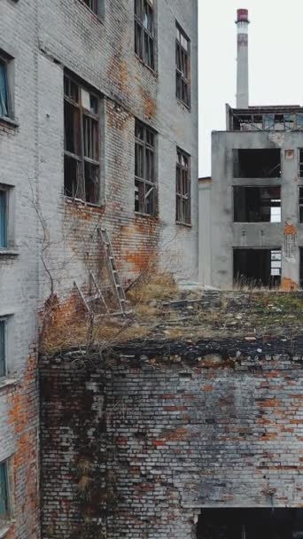 Vue aérienne d'une ancienne usine abandonnée. Fenêtres et portes cassées. Vidéo verticale.