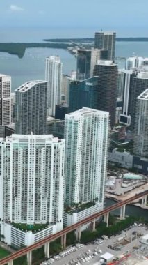 Miami, Florida, ABD - 05 Ocak 2024: Şehir merkezindeki yüksek modern binalar. Trenli metro hattı. Miami şehir merkezindeki Brickell City 'de hava görüntüsü oluşturuluyor. Dikey video.