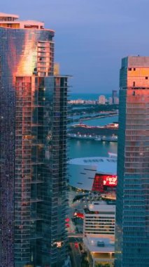 Miami, Florida, ABD - 05 Ocak 2024: Akşamları modern gökdelen binasının havadan görünüşü. Limanı ve yolcu gemisi olan körfez. Brickell şehir merkezi. Dikey video.