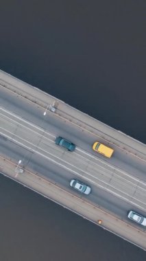 Nehir üzerindeki köprüde şehir içi araba trafiği. İnsansız hava aracıyla ateş etmek. Dikey video.