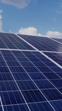 Güneş panellerinin kompleksi gökyüzünün arka planında bulutlarla sıralanmış. Alternatif enerji. Dikey video.