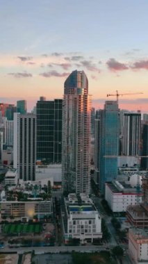 Gökdelenleri ve açık gökyüzüne karşı kentsel binaları olan hava manzaralı bir akşam şehri. Miami, Florida 'nın şehir manzarası. Dikey video.
