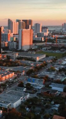 Akşam şehri Miami, gün batımında. Işınlarda yüksek binalar. Hava görüntüsü. Dikey video.