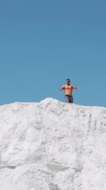 Sporcu ellerini kaldırarak zaferi sevinçle kutluyor. Dağın tepesinde koşan bir sporcu. Dikey video.