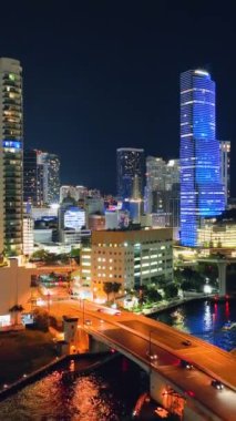 Miami, Florida, ABD - 05 Ocak 2024: Arabalı parlak sarı sokak lambaları. Parlak gökdelenleri olan bir gece şehri. Dikey video.