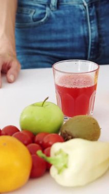 Kadın eli mutfak masasından bir bardak taze meyve suyu alır. Dikey video.