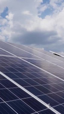 Mavi gökyüzünün arka planında bulutlu güneş silikon panelleri var. Güneş enerjisi istasyonu. Dikey video.