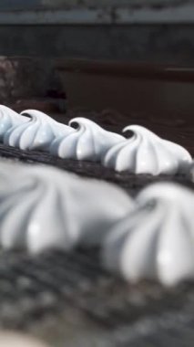 Beyaz şekerlemeleri sıcak erimiş çikolatayla kaplamak. Fabrikadaki şeker üretimi için otomatik hat. Dikey video.