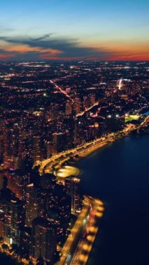 Chicago rıhtımına doğru Oak Street Plajı 'nın akşam manzarası. Parlak sokak aydınlatmaları. Binaların ışıklandırılması. Dikey video.