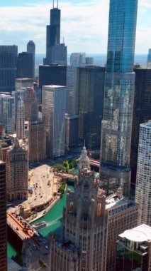 Chicago şehir merkezinde gökdelenler, nehirler ve köprüler var. Nehir taşımacılığı, tekneler. Chicago Tribune binası. Hava görüntüsü. Dikey video.
