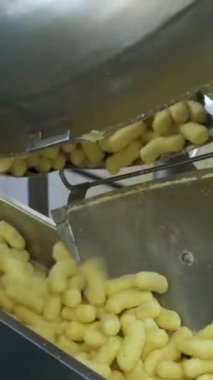 Jöleli mısır çubuğu üretimi. Yiyecek fabrikasında atıştırmalık metal taşıyıcı. Dikey video.