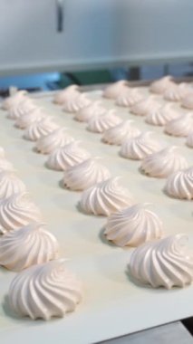 Taşıyıcı banttaki beyaz şekerleme sıralarının hareketi. Doğal şeker üretimi için bir fabrika. Dikey video.