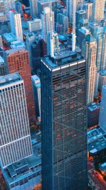 Chicago şehir merkezindeki gökdelenlerle dolu bir gökyüzü. Sokakta ve kulede antenli hava manzarası var. Dikey video.
