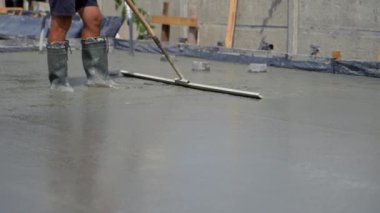 İnşaat işçisi betonu düzleştirmek için özel bir alet kullanıyor. Evin beton levhasının taşlanması. Yüzey tamlaması.