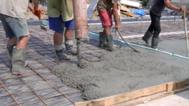 Metal bir yapı için beton dökülüyor. Güçlendirilmiş beton. Bir grup erkek inşaat işçisi özel aletler kullanarak beton döküp onları düzleştiriyor..
