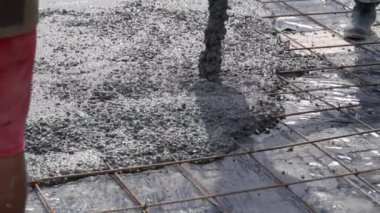 Pompadan beton dökerek güçlendirilmiş demir ızgarası olan bir levhaya dökülüyor. İnşaat çalışmalarına yakın çekim.