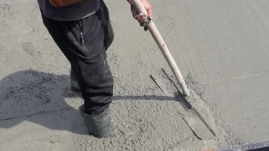 Bir işçi özel bir cihaz kullanarak taze betonu ezilmiş taşla sıkıştırır. Çimento harcı seviyesi.