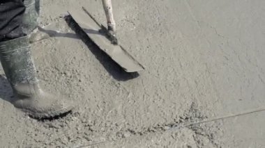 Islak beton bir yüzeyi bir aletle düzleştirmeye yakın çekim. Beton bir levhanın tıkırtısı ve pürüzsüzlüğü.