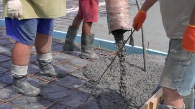 İnşaatçılar evin temelindeki beton levhayı dökerler. Demir, güç için güçlendirilmiş ağ.