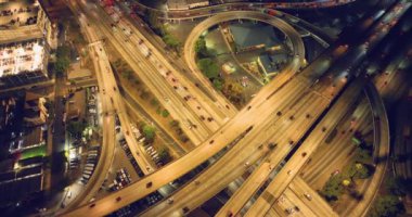 Los Angeles 'taki yolların çok katlı kavşağında gece arabaları var. I-110 kavşağı ve 10 numaralı otoyol. Hava görünümü.