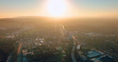 Gün batımı ufukta. Los Angeles şehrinin parlak manzarası. Gökdelenleri ve otoyolları olan şehir sokakları.