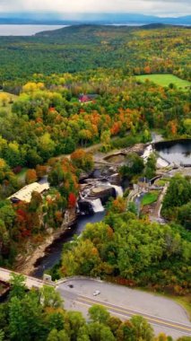 Ausable Chasm Kanyonu 'ndaki hidroelektrik santralinin yanındaki şelaleler. Sonbahar ormanı ve gölün güzel bir hava manzarası..